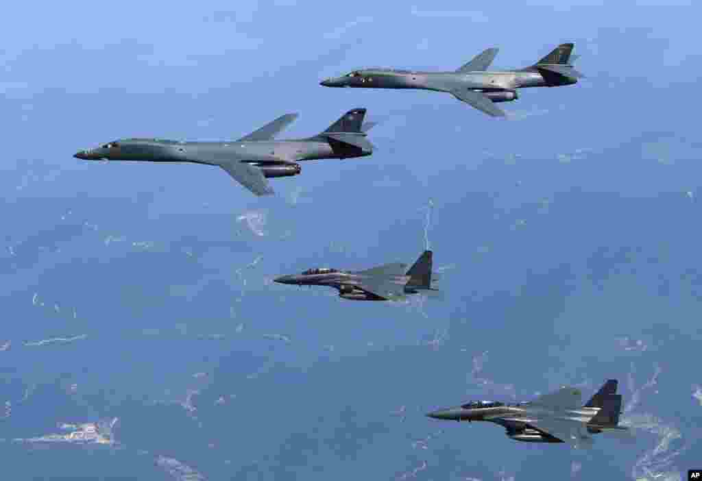 In this Tuesday, June 20, 2017 photo provided by South Korean Defense Ministry, U.S. Air Force B-1B bombers, top, and second from top, and South Korean fighter jets F-15K fly over the Korean Peninsula, South Korea.