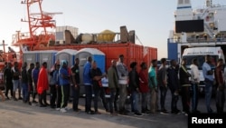 Migranti steej u redu dok im pomažu aktivisti španskog Crvenog krsta nakon što su ih spasilački brodovi dovezli u luku Algeciras, južna Španija, 22. jula 2018.