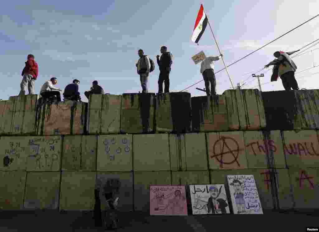 Anti-Morsi protesters shout slogans as they stand on top of a wall in front of the presidential palace in Cairo, Egypt, December 11, 2012. 