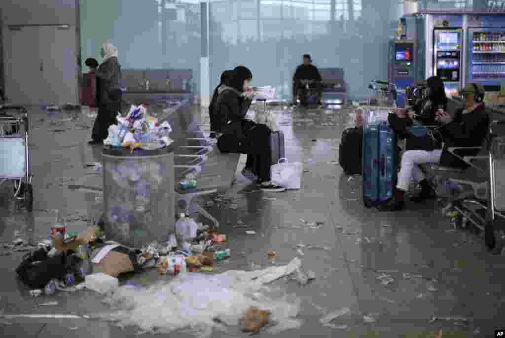 Para penumpang menunggu di bandara Prat Llobregat, Barcelona, Spanyol yang penuh sampah akibat petugas kebersihan melakukan aksi mogok kerja. 