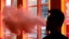 FILE - A customer exhales vapor from an e-cigarette at a store in New York, Feb. 20, 2014.