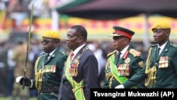UMongameli Emmerson Mnangagwa, umsekeli wakhe uRetired General Constantino Chiwenga lenkokheli yebutho. (AP Photo/Tsvangirayi Mukwazhi)