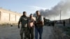 Afghan people assist an injured man after a bombing at the gate to a NATO compound in Kabul, Afghanistan, July 2, 2013.