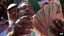FILE - An activist of Congress party holds banned 500 and 1000 rupee notes during a protest against the government's decision to withdraw high denomination notes from circulation, in front of Reserve Bank of India. in Hyderabad, Nov. 28, 2016. 