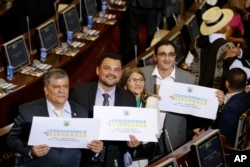 From left, Olmedo Ruiz, Sergio Marin, Sandra Ramirez and Jairo Quintero, all former members of the demobilized Revolutionary Armed Forces of Colombia, hold signs reading "Convergence for hope" at Congress before taking seats in the lower chamber of the newly elected legislature, in Bogota, Colombia, July 20, 2018.