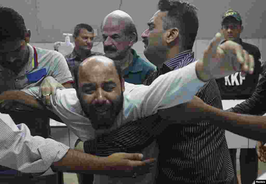 A relative mourning the death of Waqas Ali Shah, a supporter of the Muttahida Qaumi Movement (MQM) political party who was killed during a raid by paramilitary forces on MQM's headquarters, is comforted by others at a hospital morgue, in Karachi, March 11, 2015.