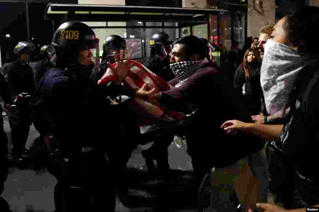 A masked demonstrator scuffles with police officers during a demonstration following the election of Donald Trump as president of the United States, in Oakland, California, Nov. 10, 2016.