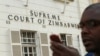 A journalist checks his mobile phone outside the Constitutional Court in Harare, Aug. 9, 2013. 