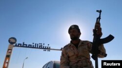 Un membre des forces libyennes fidèles au commandant de l'est Khalifa Haftar, une arme à la main, sur une voiture en face des installations pétrolières de Zueitina à Zueitina, à l'ouest de Benghazi, Libye, 14 septembre 2016.