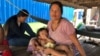 Seum Sreyoun, an unemployed garment worker, sat with her family underneath their home in Pongro village, Kampong Speu province, Cambodia, April 5, 2020. (Sun Narin/VOA Khmer)