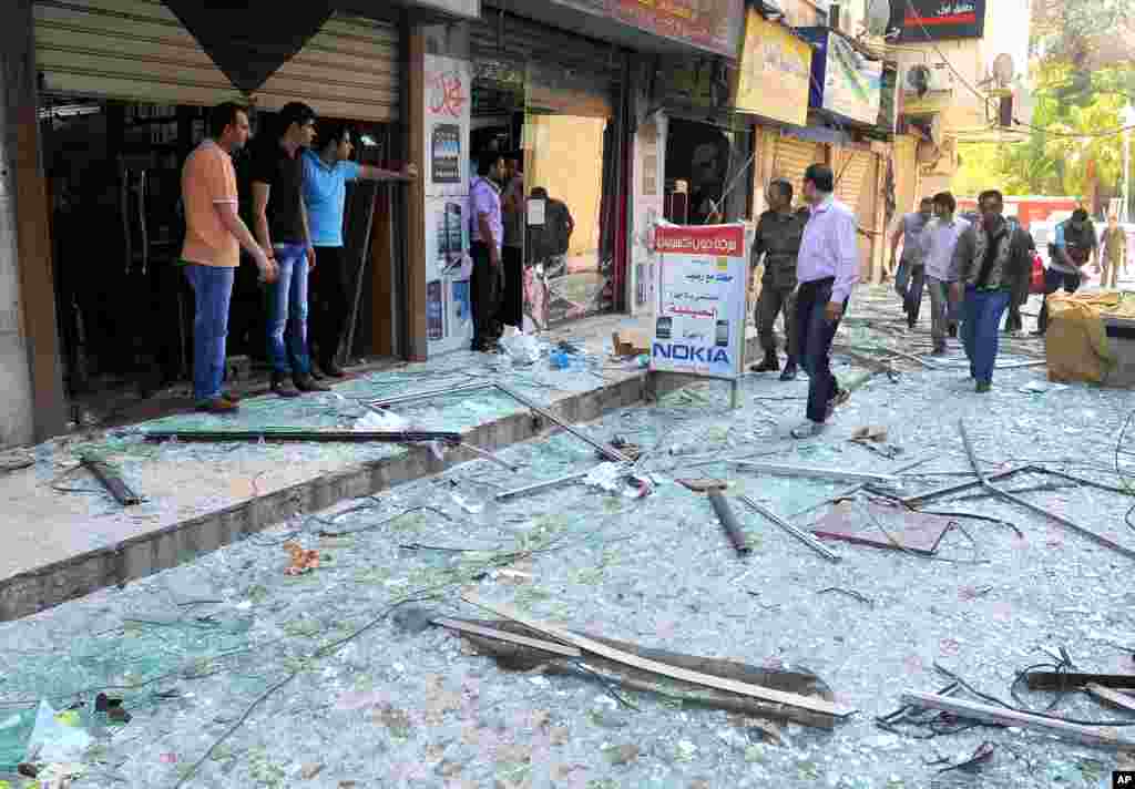 Syrian security officers, right, speak with shop owners at the scene of a powerful explosion that occurred in the central district of Marjeh, in Damascus, Syria, April 30, 2013.