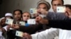 Afghan men display their identification cards as the wait to cast their votes outside a polling station in Kabul, Afghanistan, Saturday, June 14, 2014.
