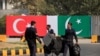 FILE - Police walk near the national flags of Pakistan and Turkey displayed along a road in Islamabad, Pakistan, Nov. 16, 2016. 