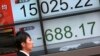 People walk past an electronic stock board showing Japan's Nikkei 225 in Tokyo, Friday, Feb. 12, 2016.