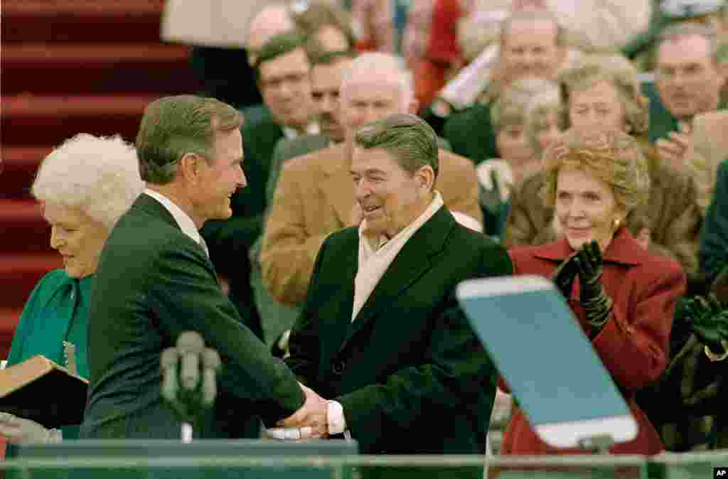 Presiden George Bush (kiri) menerima ucapan selamat oleh Presiden Ronald Reagan setelah Bush diambil sumpahnya sebagai presiden AS ke-41 di Capitol Hill di Washington, D.C., 20 Januari 1989.