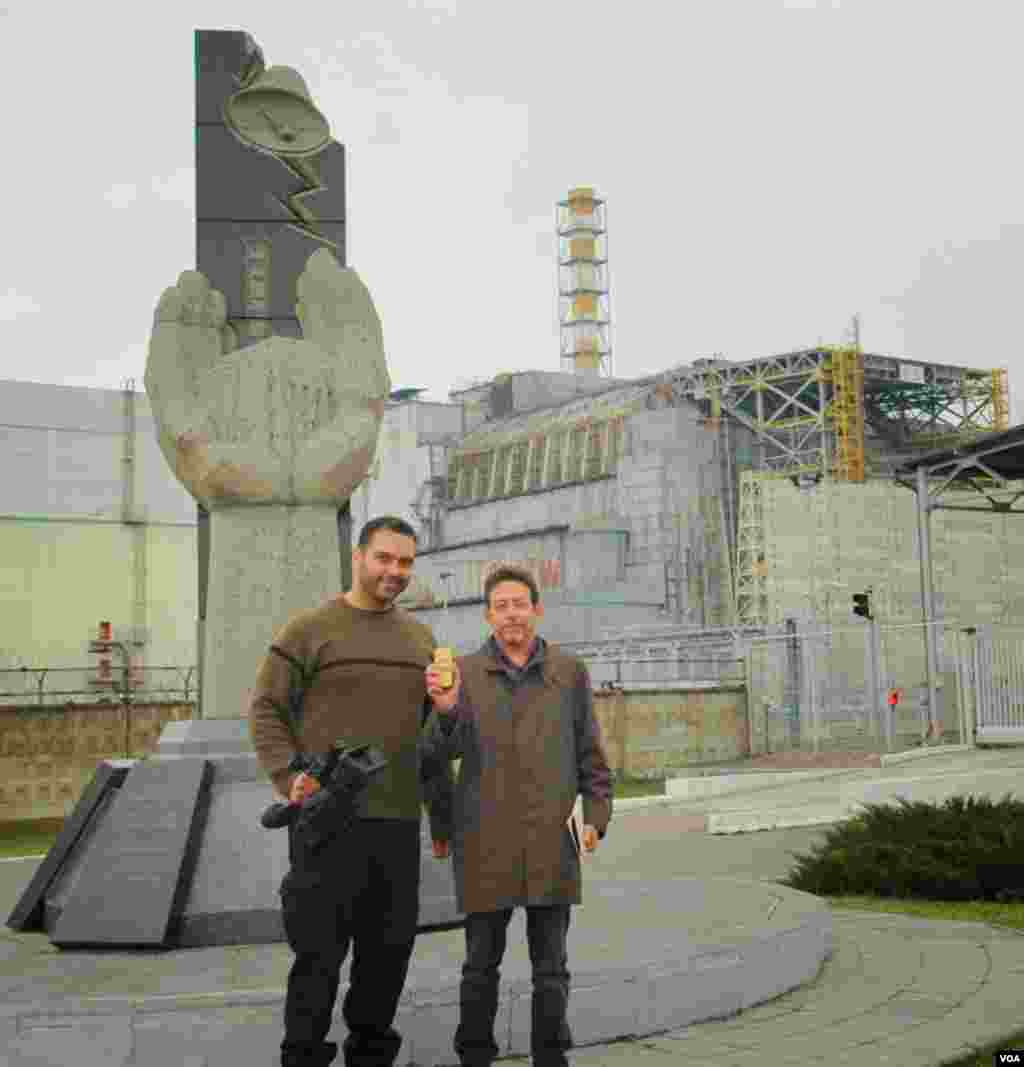 VOA's videographer Arash Arabasadi and correspondent Steve Herman (holding a radiation monitor) in front of the old sarcophagus covering Chernobyl Reactor No. 4, Chernobyl Nuclear Power Plant, Ukraine, March 19, 2014. (unknown photographer/VOA)