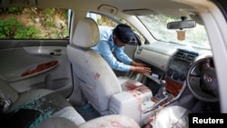 A policeman collects evidence from the car in which prosecutor Chaudhry Zulfikar was traveling, when he came under attack from unidentified gunmen in Islamabad, May 3, 2013.