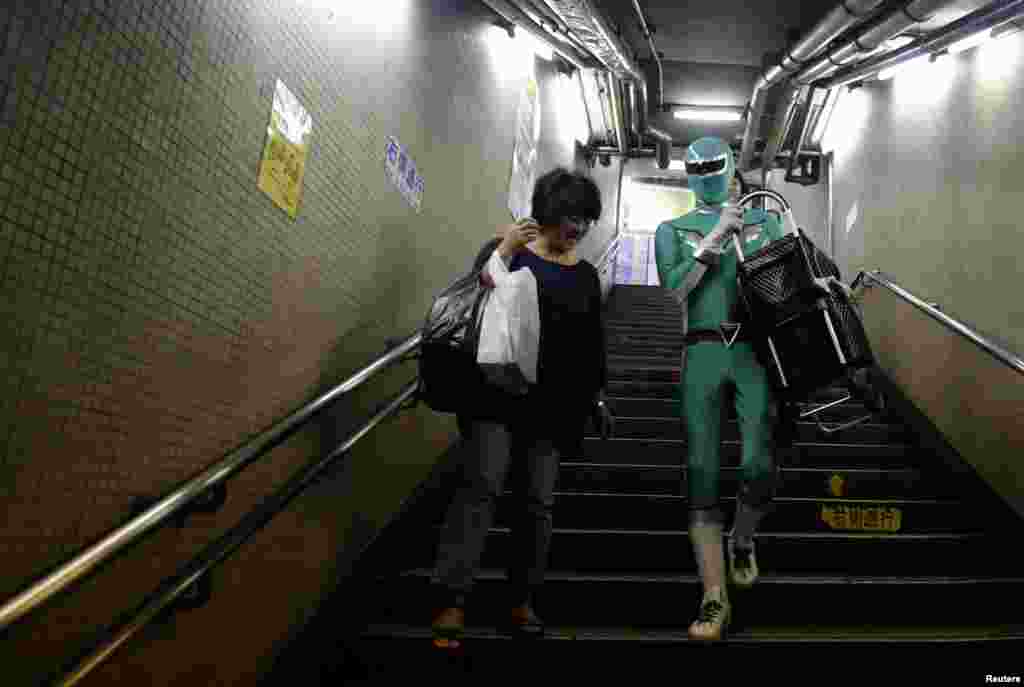 Tadahiro Kanemasu alias &#39;&quot;Superhero pembantu pengangkut barang&quot; membawa keranjang belanja seorang ibu di sebuah stasiun di Tokyo, Jepang. Mengenakan pakaian hijau ketat dengan aksen perak dan topeng yang sesuai,&nbsp; sang &quot;superhero&quot; menunggu di tangga stasiun kereta bawah tanah Tokyo, untuk membantu para penumpang yang lanjut usia, membawakan barang-barang yang berat atau membantu para ibu dengan kereta bayi.