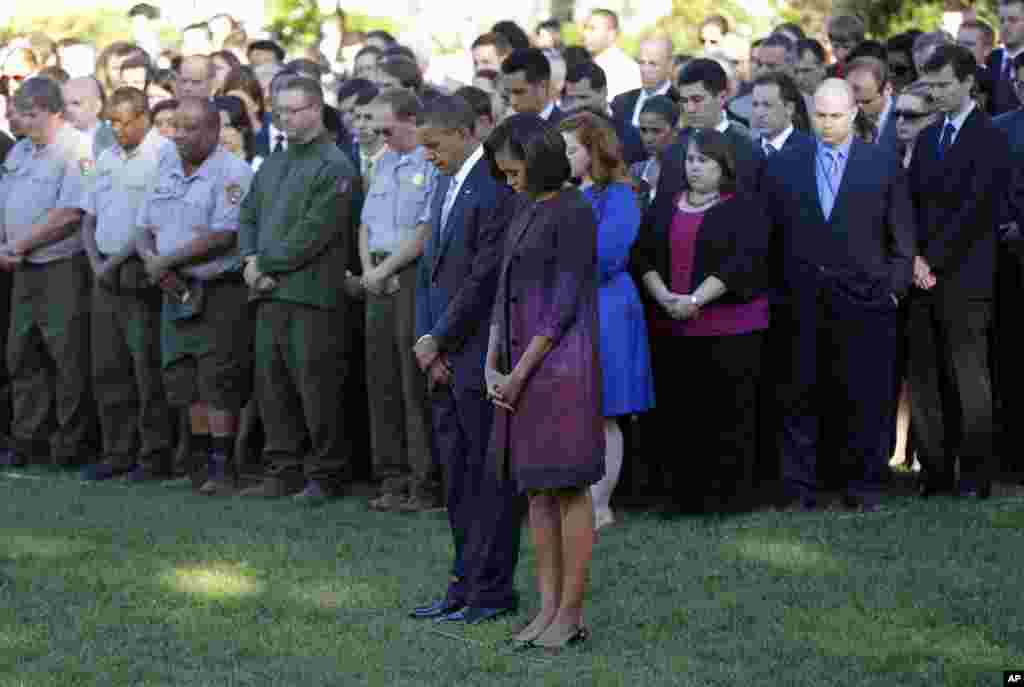 President Barack Obama, first lady Michelle Obama, and members of the White House staff pause during a moment of silence to mark the 11th anniversary of the September 11 attacks on the South Lawn of the White House in Washington.