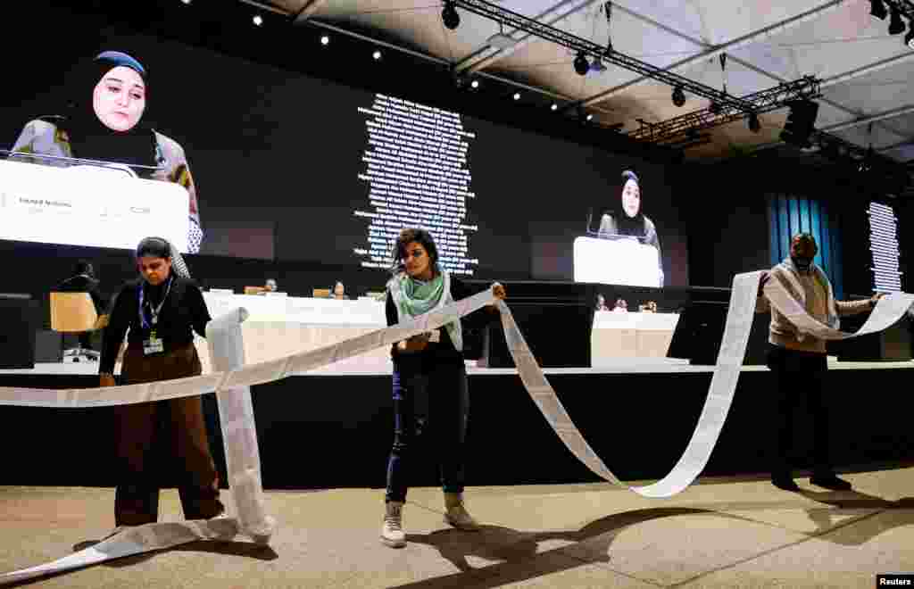 Activists hold a roll of paper with the names of the victims of the conflict between Israel and Hamas as an activist delivers a speech during the &quot;People&#39;s Plenary&quot; at the COP29 United Nations climate change conference, in Baku, Azerbaijan.