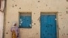 Une femme se tient devant une maison endommagée par les tirs lorsque les forces fédérales sont entrées dans la ville de Wukro, au nord de Mekele, dans le Tigré, le 1er mars 2021. 