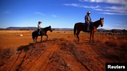 FILE - Farmer Scott Cooper and his daughter Charlie ride their horses along a fence in a drought-affected paddock on their property named "Nundah," south of the central New South Wales town of Gunnedah in Australia, July 21, 2018.