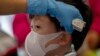 A health worker checks the temperature of tourist from Wuhan, China, as he waits for a charter flight back to Wuhan at the Suvarnabhumi airport, Bangkok, Thailand, Jan. 31, 2020.