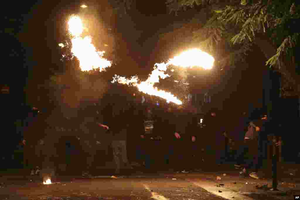 Para pemuda yang menutupi wajahnya melemparkan bom molotov ke arah polisi pada bentrokan di Athena, Yunani.