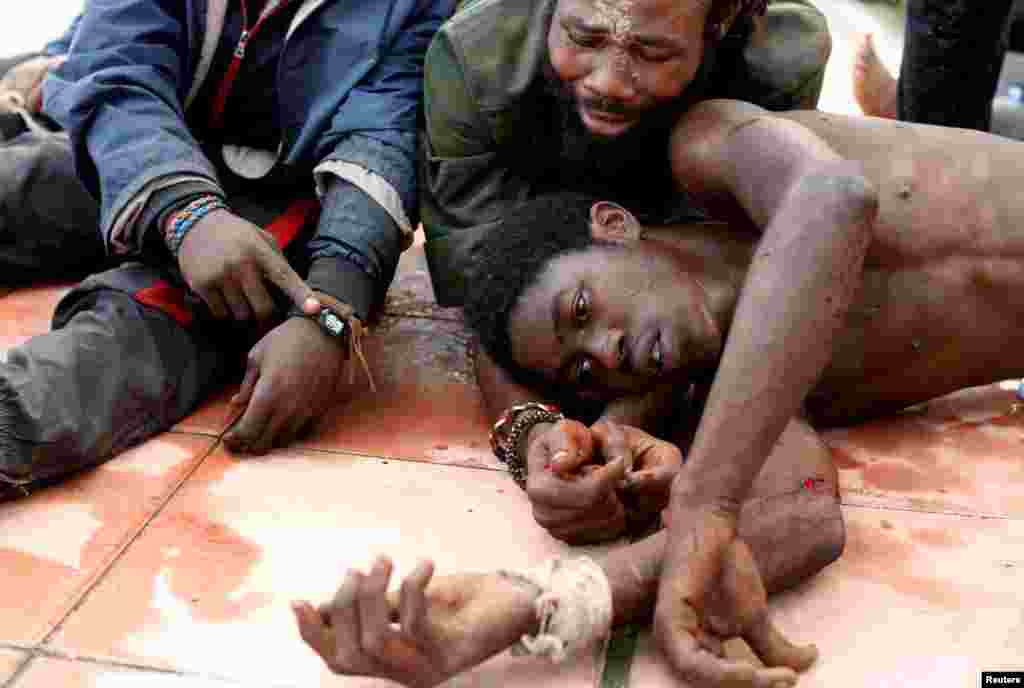 African migrants lie on the ground after crossing a border fence between Morocco and Spain's North African enclave of Ceuta, Oct. 31, 2016.