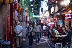 Warga mengenakan masker sebagai tindakan pencegahan terhadap virus Covid-19 saat mengunjungi kawasan restoran Omoide Yokocho di distrik Shinjuku, Tokyo, 19 November 2020.