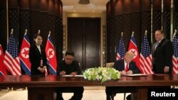 U.S. President Donald Trump and North Korea's leader Kim Jong Un sign documents that acknowledge the progress of the talks and pledge to keep momentum going, after their summit at the Capella Hotel on Sentosa island in Singapore, June 12, 2018.