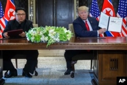 Predsjednik SAD, Donald Trump, drži dokument koji su on i sjevernokorejskli lider Kim Jong Un potpisali u odmaralištu Kapela na Sentosa ostrvu, 12. juna 2018, u Singapuru.