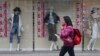 A shopper walks past a clothing shop display on a shopping street in Tokyo Monday, Feb. 15, 2016.