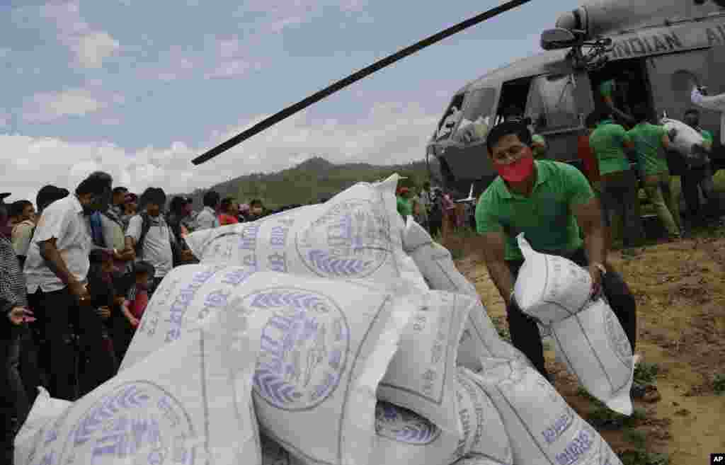 Para tenaga sukarela Nepal mengeluarkan bahan bantuan yang dibawa oleh helikopter angkatan udara India untuk para korban gempa, di Trishuli Bazar di Nepal (27/4). (AP/Ajit Solanki)