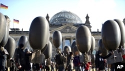 Demonstrators hold balloons in front of the Reichtags building to protest against arms trade, Germany, February 26, 2012.