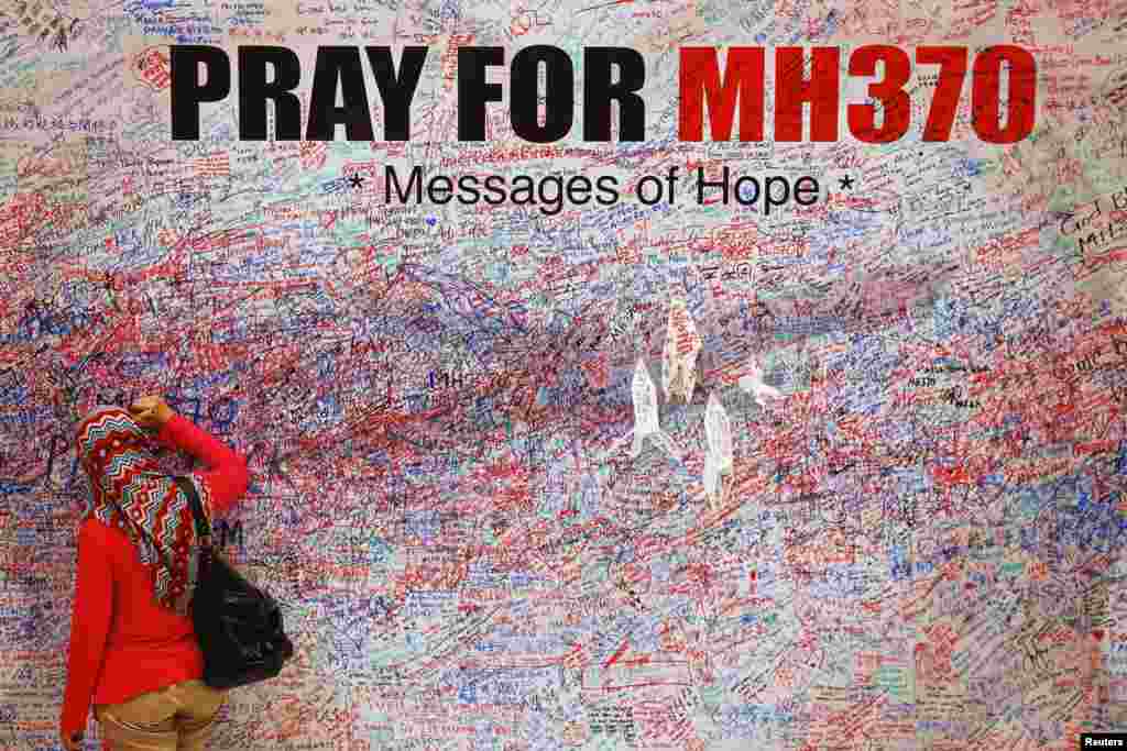 Một phụ nữ viết thông điệp cầu nguyện cho các hành khách trên chuyến bay Malaysia MH370 bị mất tích tại Kuala Lumpur, Malaysia.