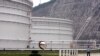 FILE - a security guard stands guard near oil tanks at Zhoushan Oil Reserve in Zhoushan in Zhejiang Province, China, June 30, 2009. Cooling economies in Asia and Europe also have weakened demand, sending the price below $50 for the first time since April.