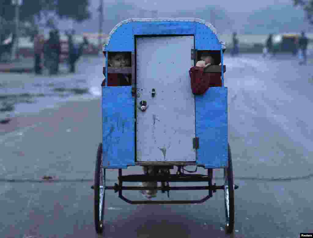 Murid-murid berangkat ke sekolah dengan naik 'rickshaw' (sejenis becak) pada suatu pagi yang dingin di kota tua Delhi (Old Delhi), di India.