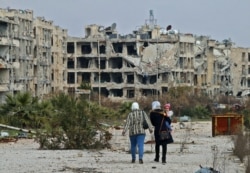FILE - Residents of a suburban neighborhood on the edge of the northern Syrian city of Aleppo return to their homes to check the damage caused by fighting between regime forces and rebel fighters.