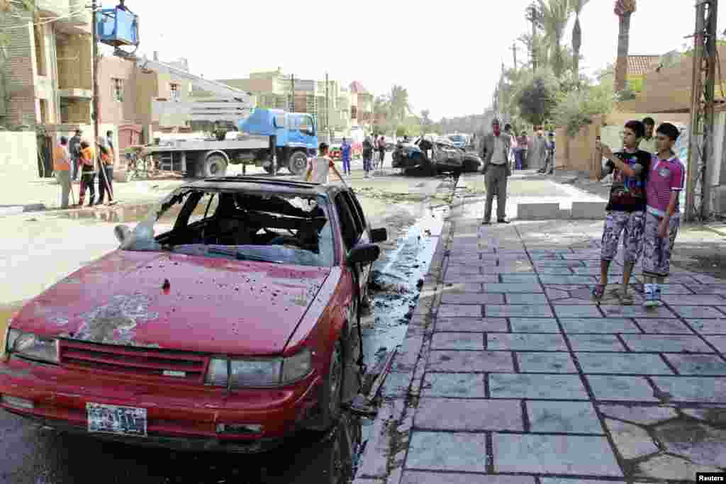 A youth takes pictures with his mobile phone at the site of a car bomb attack in Baghdad's Al-Baladiyat District, Oct. 27, 2013.