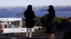 FILE - The Sydney Opera House and Harbour Bridge can be seen behind real estate agent LuLu Sun (R) as she escorts Bao Fang, a potential buyer from Shanghai, during an inspection of a property for sale in the Sydney suburb of Vaucluse, Australia, July 11, 