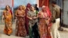 A policeman checks identity papers of women as they arrive to cast their votes at a polling station during the first phase of Gujarat state assembly election in Panshina village of Surendranagar district, Dec. 9, 2017.