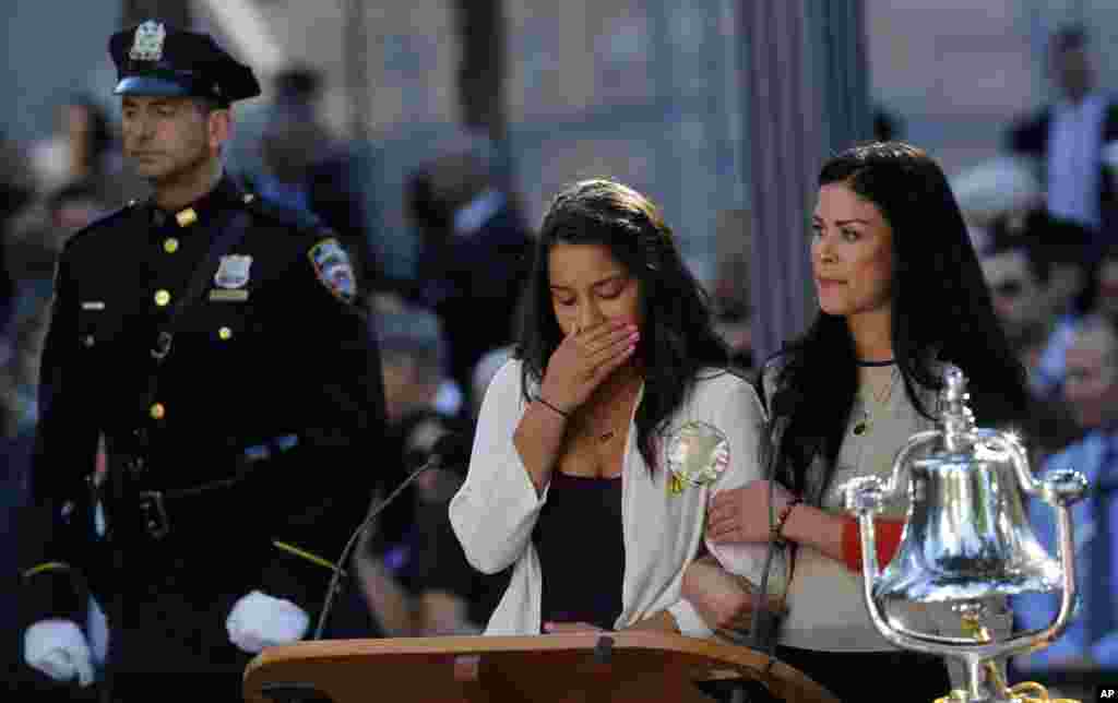 A woman becomes emotional after reading the name of her father as friends and relatives of the victims of the September 11 attacks gather at a memorial, New York, September 11, 2012.