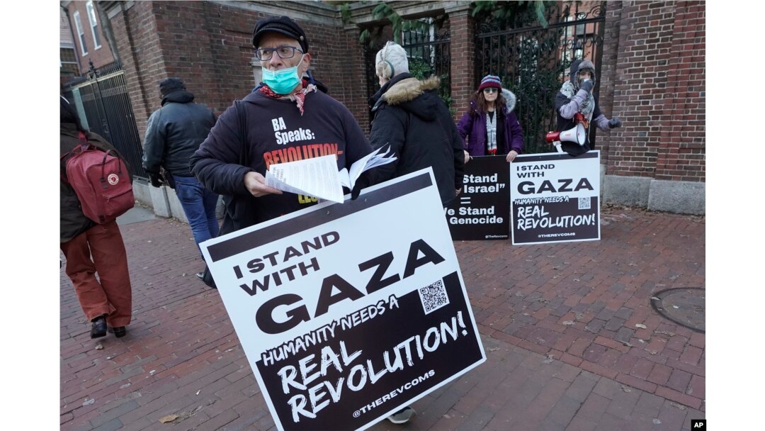FILE - George Stevens, of Cambridge, Mass., front, hands out leaflets to passers-by near an entrance to Harvard University, Tuesday, Dec. 12, 2023, in Cambridge. (AP Photo/Steven Senne)