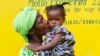 Mamie Harris, a caregiver at Liberia’s Hawa Massaquoi transit center in Unification Town, Margibi County, holds 18-month-old Agnes. The center, run by the government with UNICEF support, aids children affected by Ebola. (© UNICEF /Jallanzo)