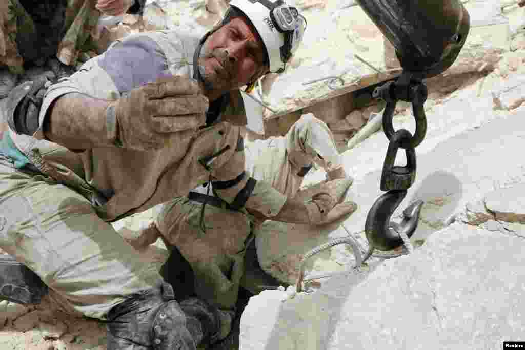 A rescuer gestures at a site hit by what activists said was a barrel bomb dropped by forces loyal to Syria's President Bashar al-Assad in Aleppo's Karam al-Beik neighborhood.