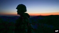 FILE - A Russia-backed rebel guards the position after sunset near Donetsk, eastern Ukraine, Aug. 2, 2015. Hostilities in eastern Ukraine have abated after February's peace agreement, but the truce has been frequently violated.