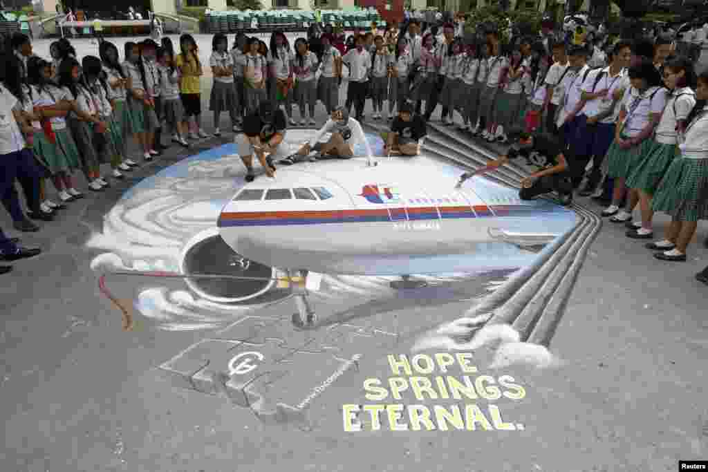 Sekelompok seniman menyelesaikan karya seni berdasarkan pesawat Malaysia Airlines penerbangan MH370 yang hilang, yang dilukis di atas lapangan sekolah di Makati, metro Manila, Filipina (17/3). (Reuters/Romeo Ranoco)