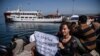 A woman activist holds a placard as a small Turkish ferry carrying migrants who are deported to Turkey arrives on April 4, 2016 at the port of Dikili district in Izmir.