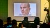 FILE - Journalists look a image of Indian naval officer Kulbhushan Jadhav, who was arrested in March 2016, during a press conference by Pakistan's army spokesman and the Information Minister, in Islamabad, Pakistan, March 29, 2016.